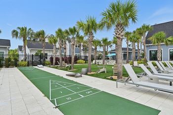 A tennis court is surrounded by palm trees and lounge chairs.  at The Sophia, Venice, FL, 34275